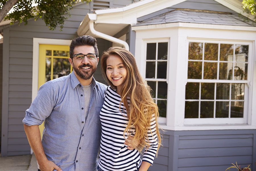 Personal Insurance - Portrait Of Couple Standing Outside Their New Home